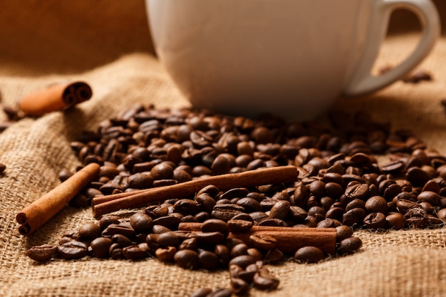 Cup, coffee beans and cinnamon sticks