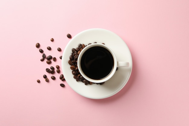 Cup of coffee and beans on pink