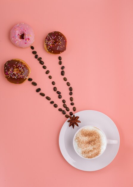 Cup of coffee, beans and three doughnut  on pink background