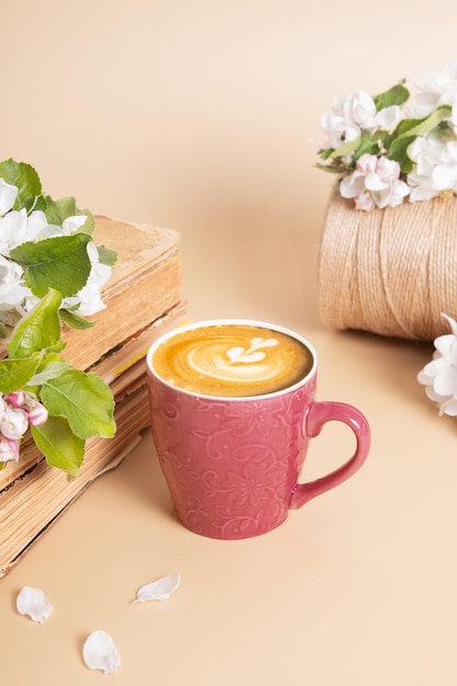 Cup of coffee and blossom apple twigs with vinage books Springtime still life composition