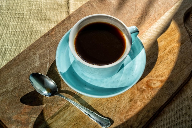 Cup of coffee on a board illuminated by the sunlight, autumn day.