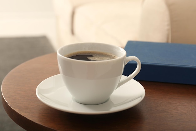 Cup of coffee and book on table in room