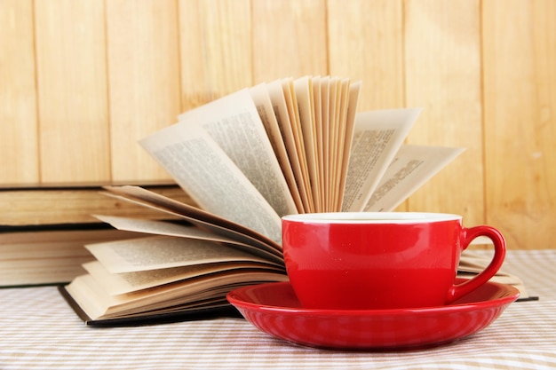 Cup of coffee and books on tablecloth on wooden background