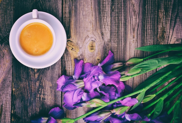 一杯のコーヒーとブルーアイリスの花束