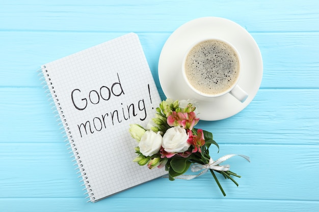 Photo a cup of coffee a bouquet of flowers and a card with the words good morning