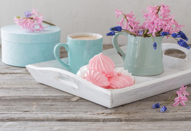 A cup of coffee and a bouquet of flowers on a wooden table