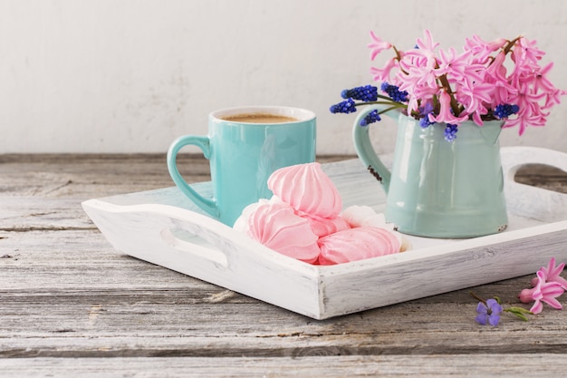 A cup of coffee and a bouquet of flowers on a wooden table