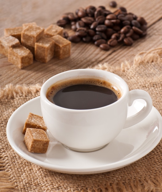 Cup of coffee, brown sugar and coffee beans