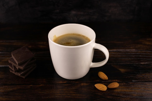 Cup of coffee cappuccino almonds and dark chocolate  on a dark wooden background