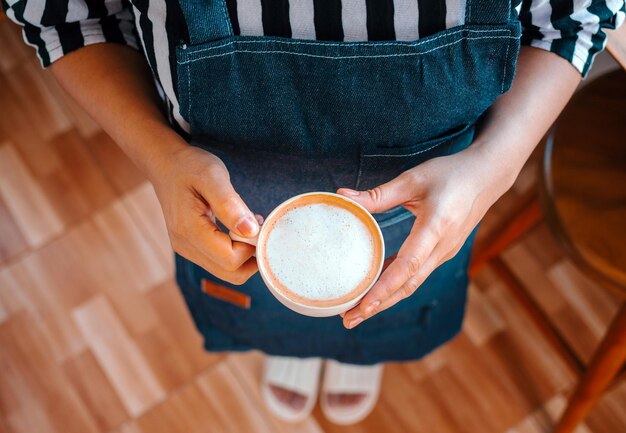 Foto una tazza di caffè menu cappuccino pronto a servire in mano donna barista nella caffetteria