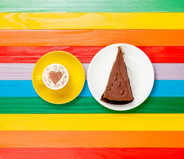 Cup of coffee cappuccino with cake on rainbow