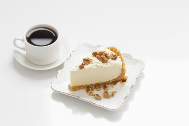 Cup of coffee and cheesecake on white table