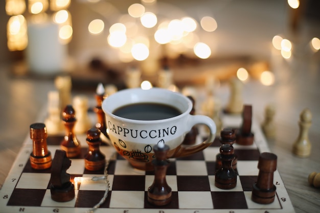 cup of coffee and chess on a chessboard game concept hobby coffee break