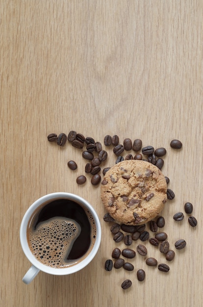 木製の背景にコーヒーとチョコレートチップクッキーのカップ