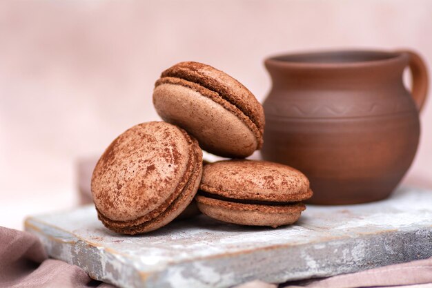 A cup of coffee and chocolate macarons on a wooden board Breakfast concept