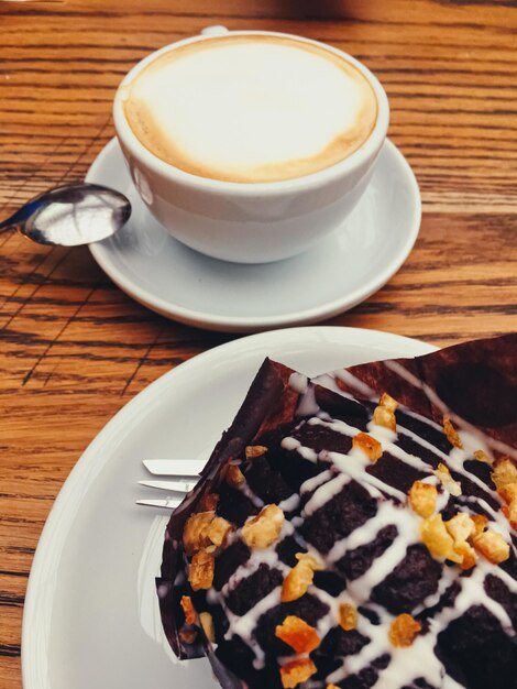 Cup of coffee and chocolate muffin on wooden table in city cafe