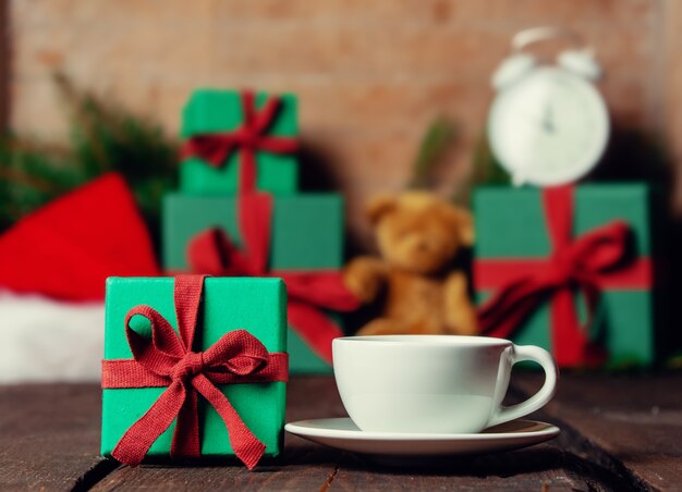 Cup of coffee and Christmas gifts on background on wooden table.