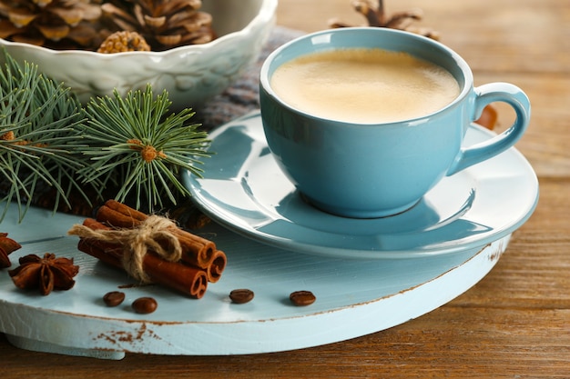 Cup of coffee and Christmas tree branch on wooden mat