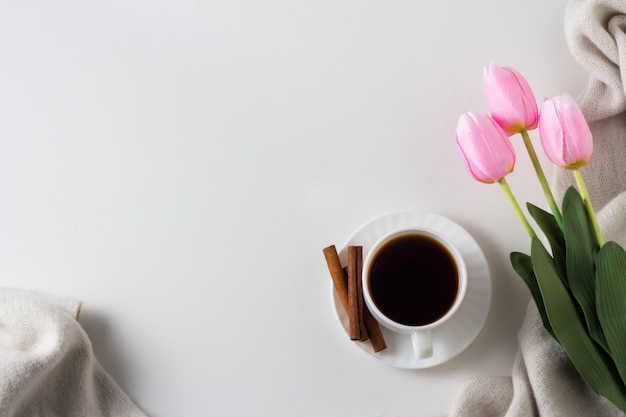 Cup of Coffee, Cinnamon, Scarf, Tulips on the White surface. Spring Concept. Flat lay, top view