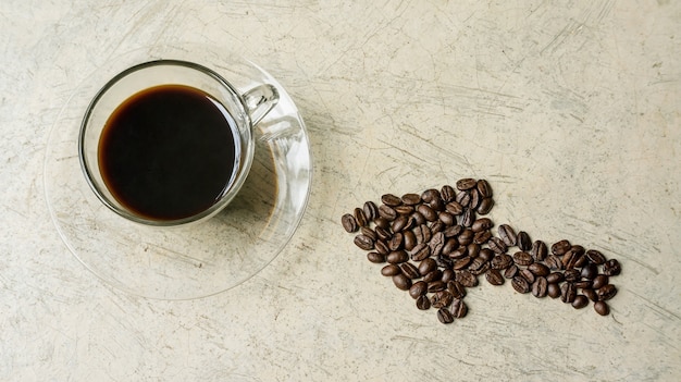 A cup of coffee and a coffee bean on a gray background.