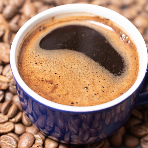 A cup of coffee and coffee beans on a black background an aromatic and energy drink