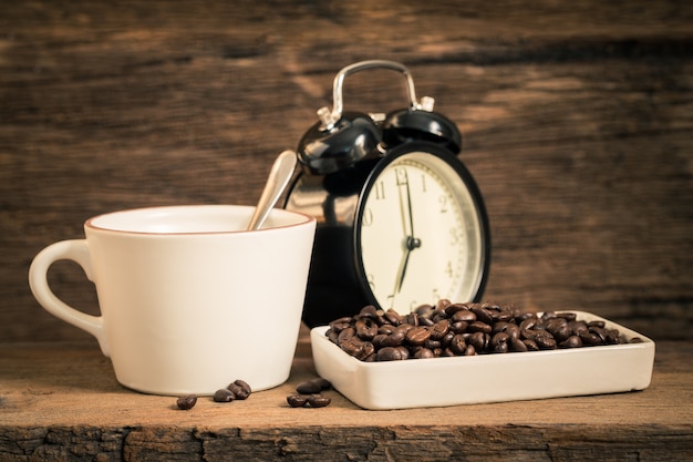 A cup of coffee and coffee beans on an old wooden table.