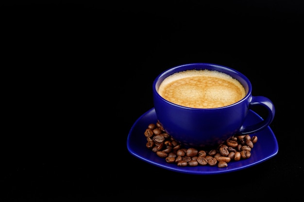 Tazza di caffè e chicchi di caffè su un piatto su uno sfondo nero