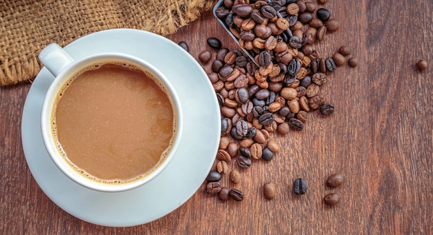 Cup of coffee and coffee beans in a sack on Brown background top view