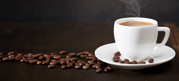 Foto tazza di caffè e chicchi di caffè sul tavolo. sfondo nero.