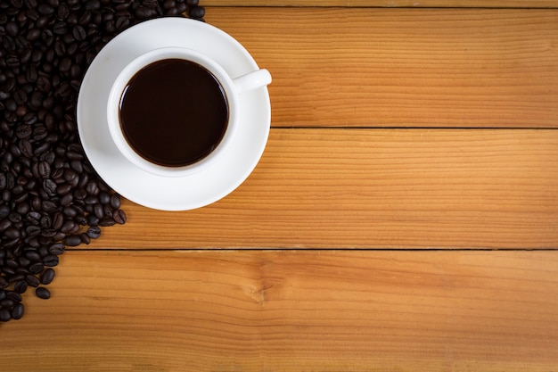 Cup of coffee and coffee beans on wood 