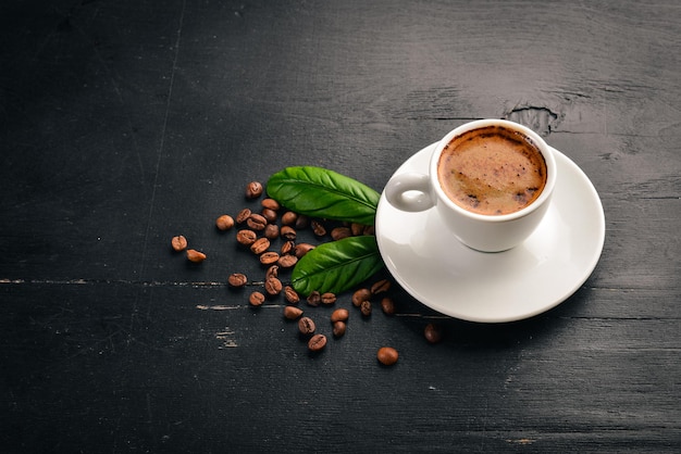 A cup of coffee and coffee beans on a wooden background. Top view. Free space for text.