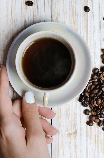 Cup of coffee and coffee beans on wooden board.