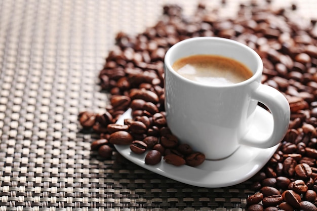 Cup of coffee and coffee grains on dark background