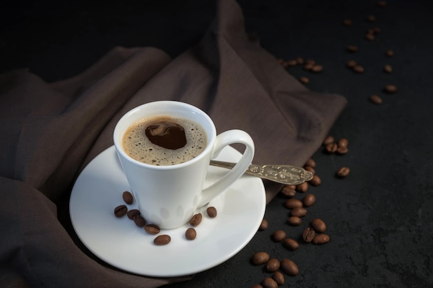 A cup of coffee a coffee grinder and roasted coffee beans on the black background Espresso