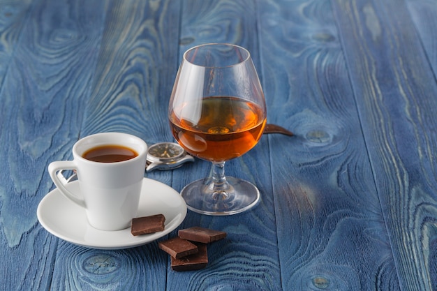 Cup of coffee, cognac glass and chocolate on a wooden table