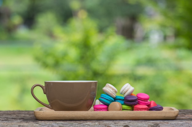 Photo cup of coffee and colorful macaroons in dish on wooden table