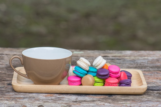 Cup of coffee and Colorful Macaroons in dish on wooden table