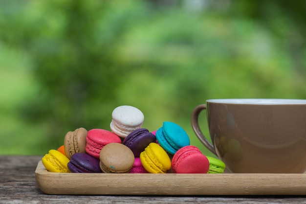 Cup of coffee and Colorful Macaroons in dish on wooden table