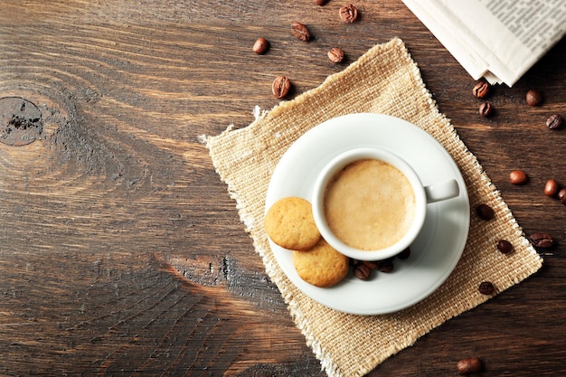 Cup of coffee cookie and newspaper on wooden table background