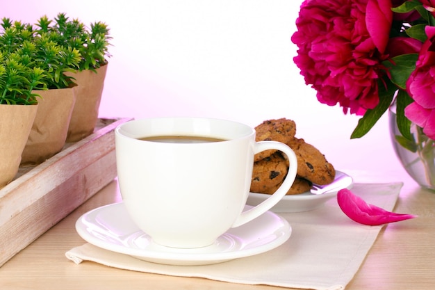 Cup of coffee cookies and flowers on table in cafe