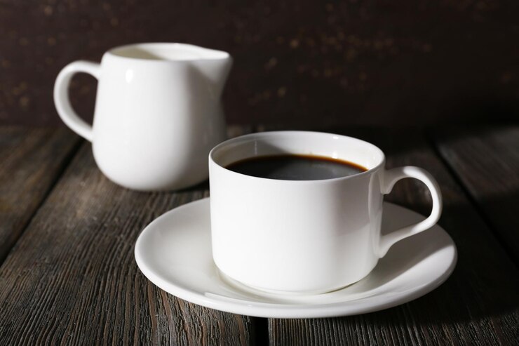 Photo 一杯のコーヒーと暗い背景に木製のテーブルのミルク水差しにクリーム