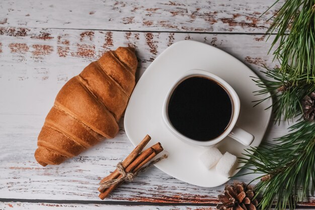 Tazza di caffè e un cornetto sul tavolo