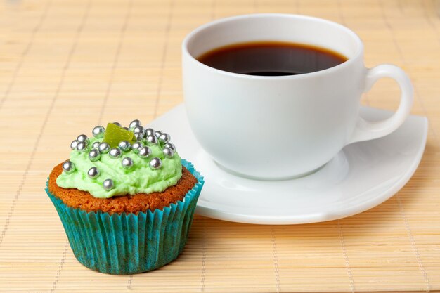 Cup of coffee and cupcake with cream and decorative toppings