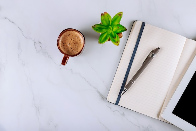 Cup of coffee and digital tablet with notebook, pen, office desk table