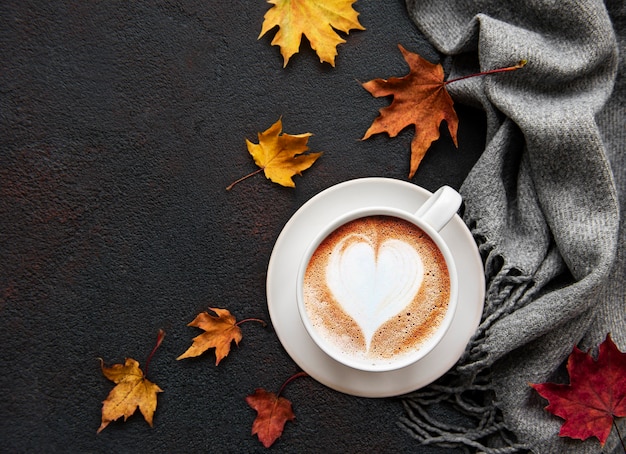 黒いコンクリートの背景にコーヒーと乾燥した葉のカップ。