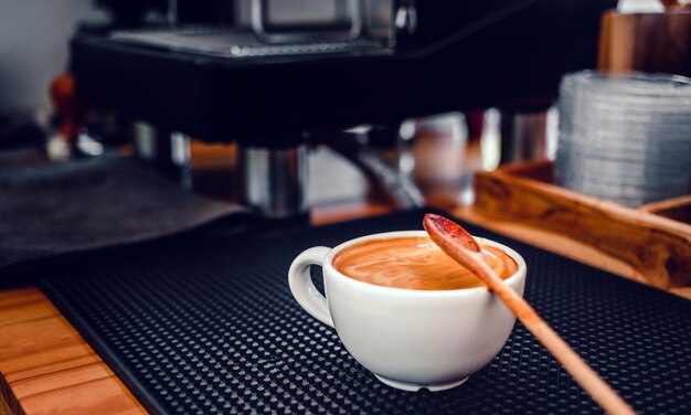 A cup of coffee espresso and a wooden spoon on the bar in a coffee shop