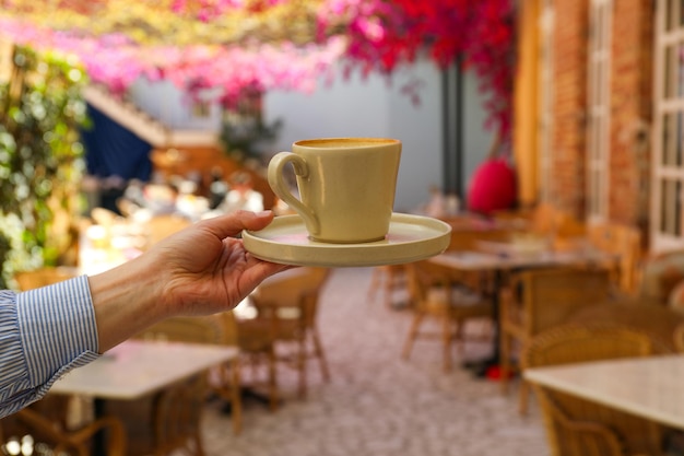 Cup of coffee in female hand outdoors