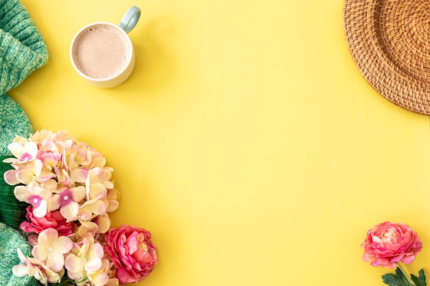 Tazza di caffè fiori ed elemento lavorato a maglia su sfondo giallo piatto