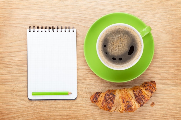 Cup of coffee fresh croissant and notepad