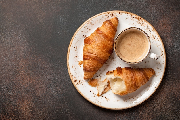 Cup of coffee and fresh croissants on a plate